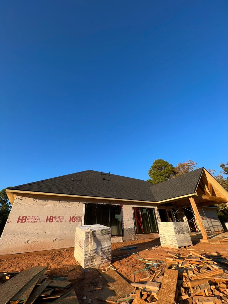 Partially built house with exposed framing and scattered bricks under a blue sky