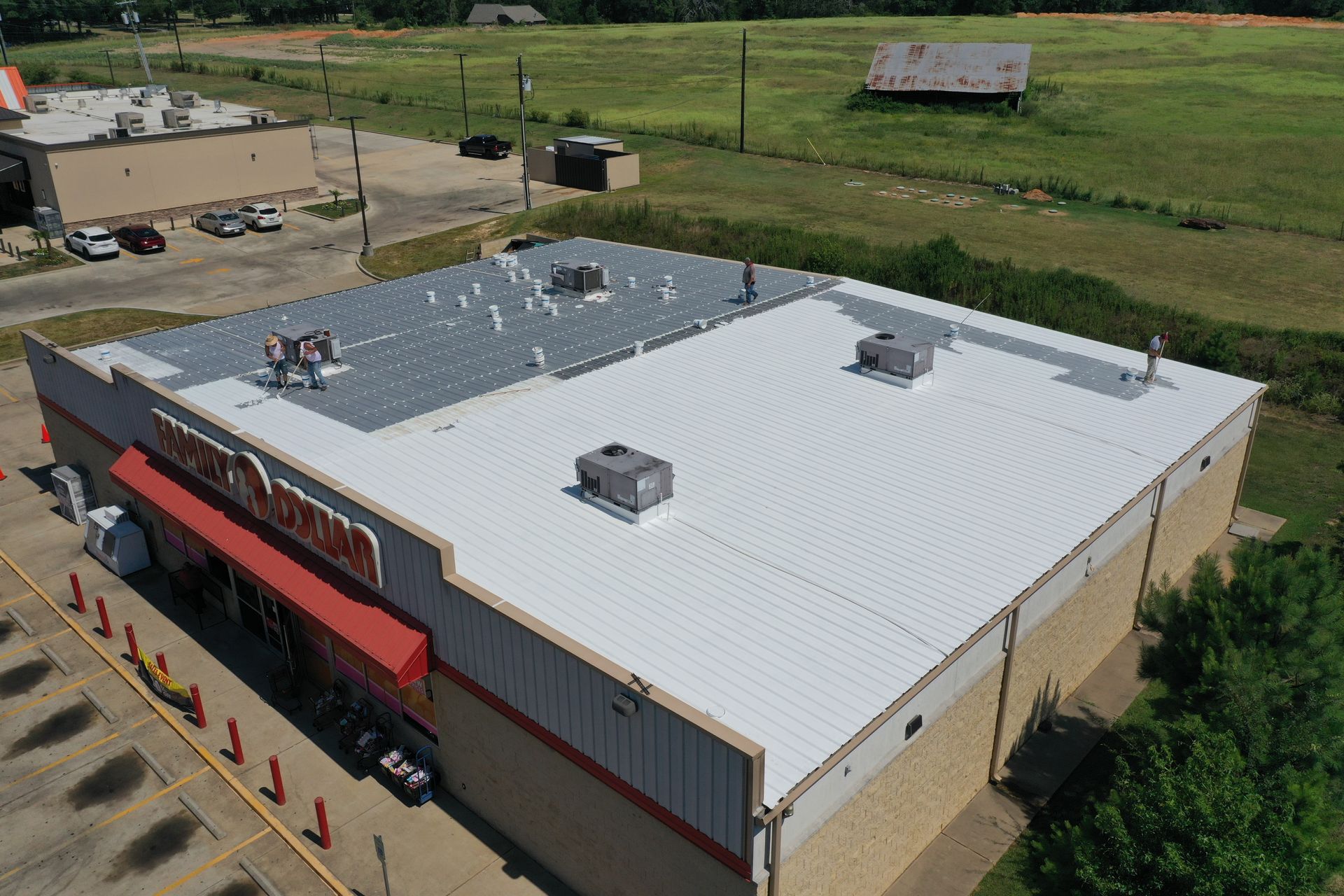 Aerial view of a large white-roofed commercial building in a rural area with fields and a parking lot nearby.