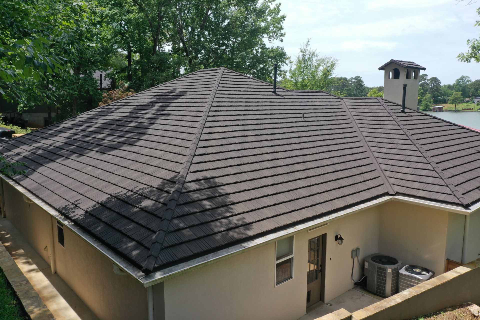 House with dark gray shingle roof and trees in the background