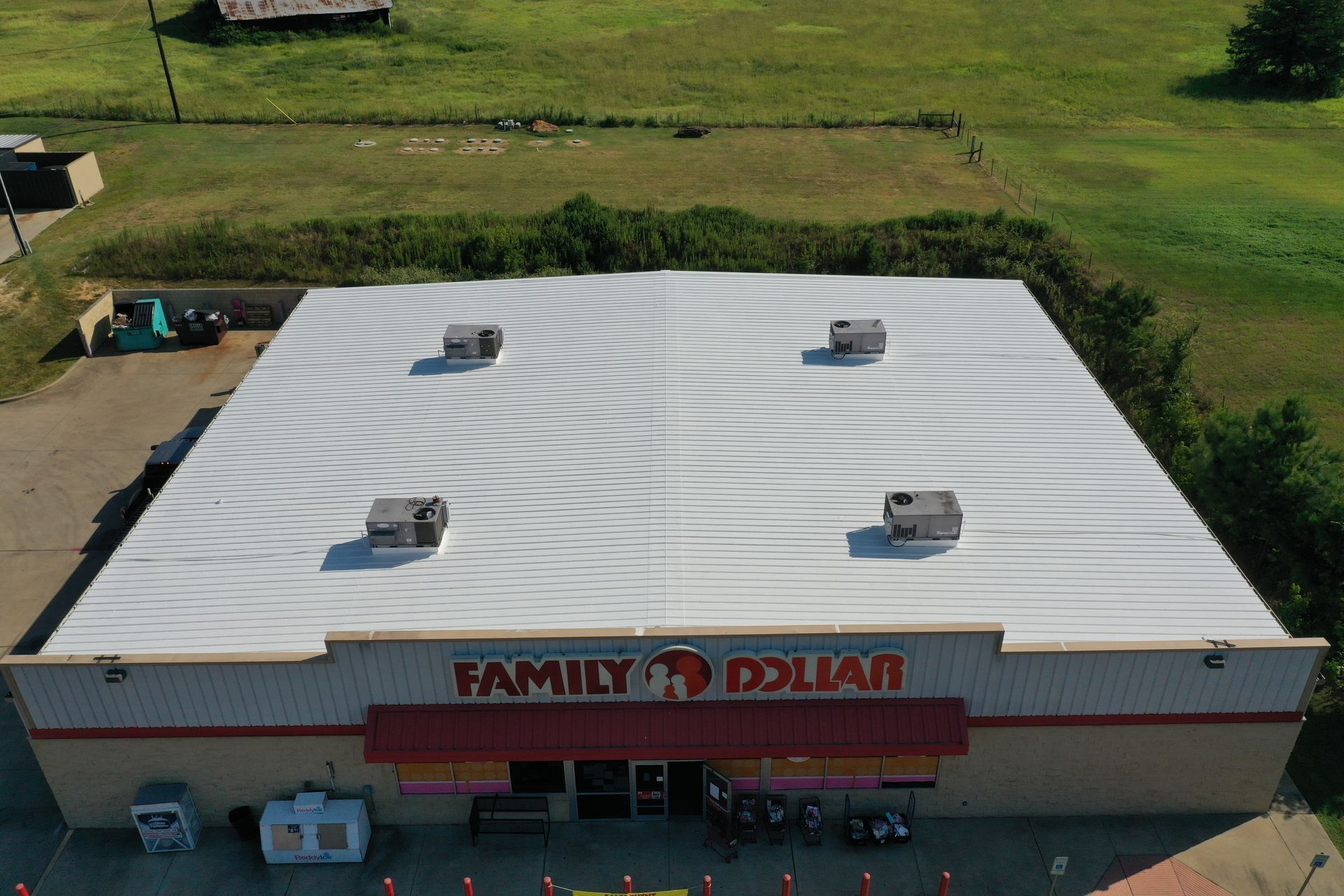 Aerial view of a Family Dollar store with a white roof and parking lot in front.