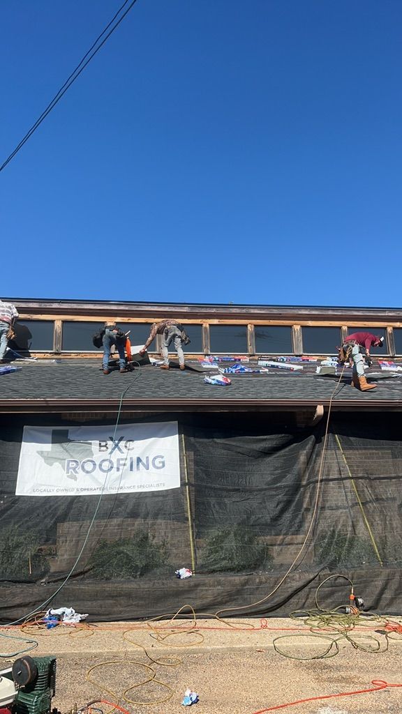 Workers on a roof repairing a damaged building under a clear blue sky