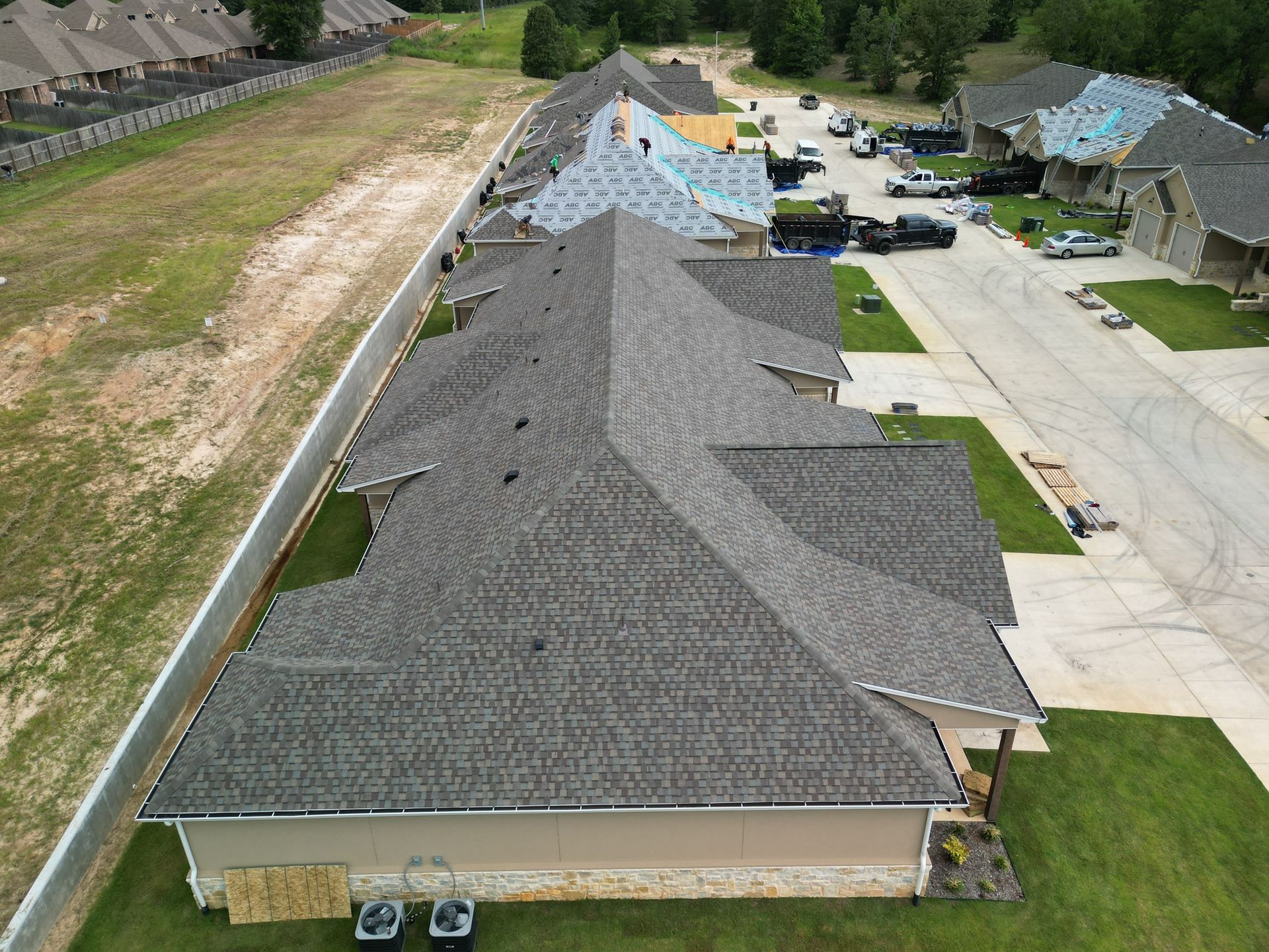 Aerial view of a residential neighborhood with row houses, driveways, lawns, and a street