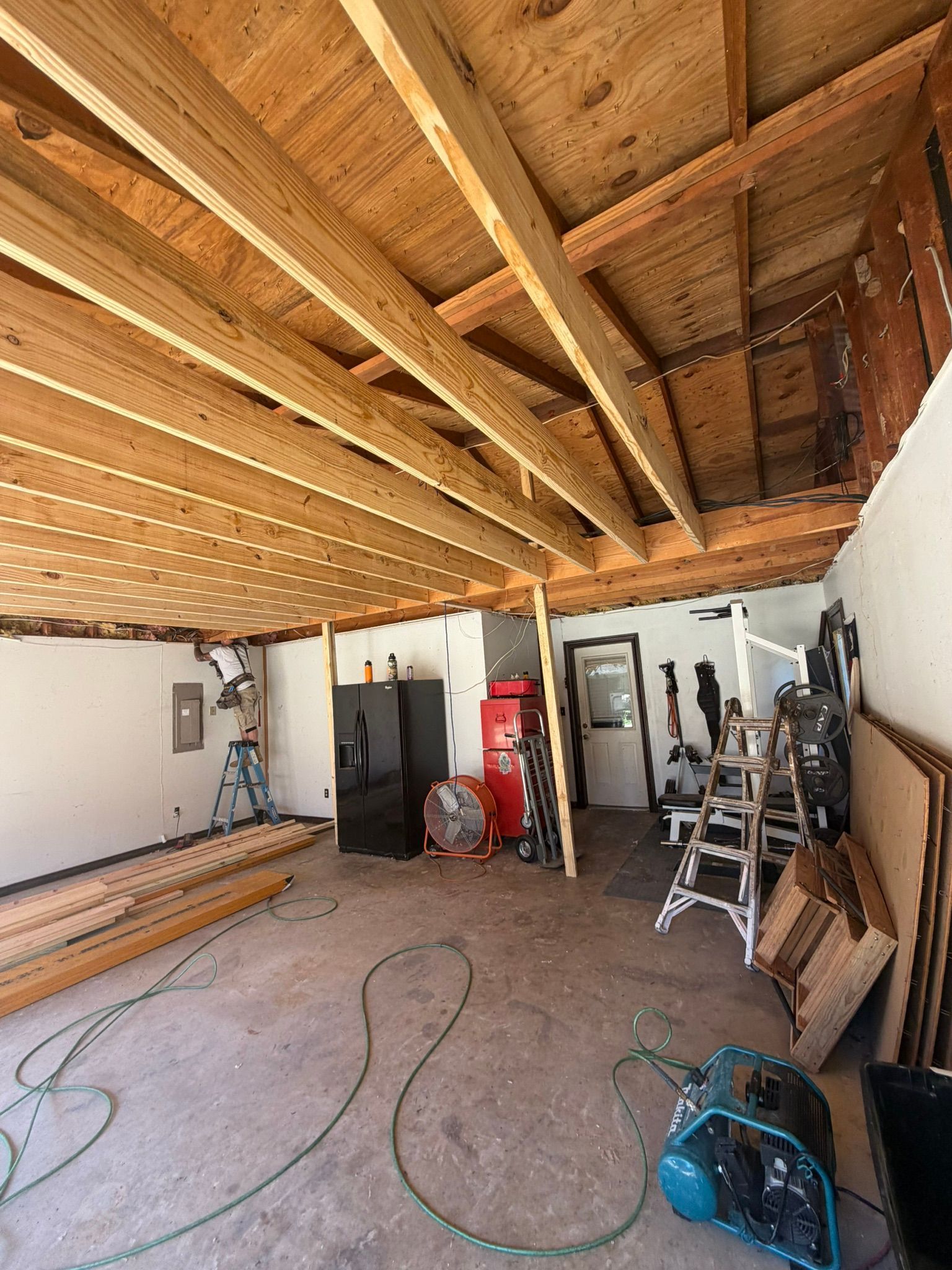 Partially finished garage with exposed ceiling beams, tools, and construction materials scattered around