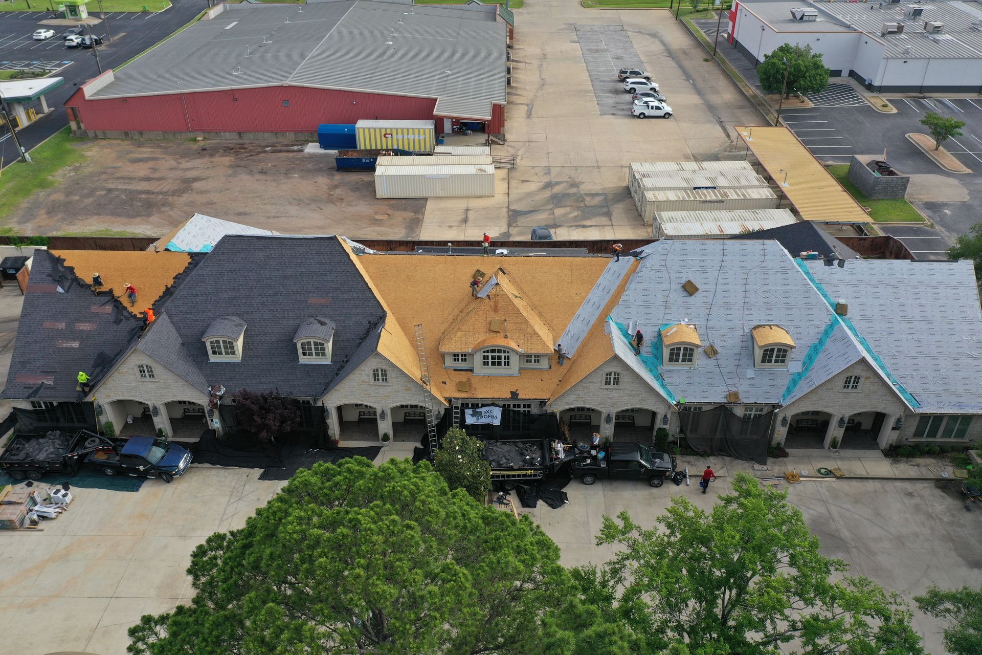 Aerial view of colorful townhouse row with parked cars and industrial buildings nearby