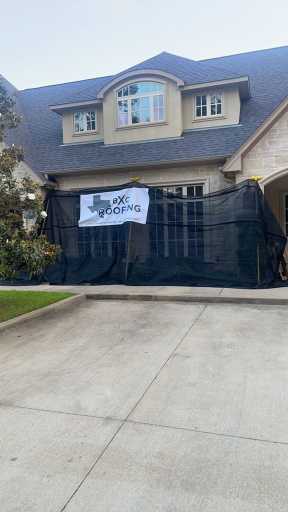 House with black construction fencing and a banner across the driveway.
