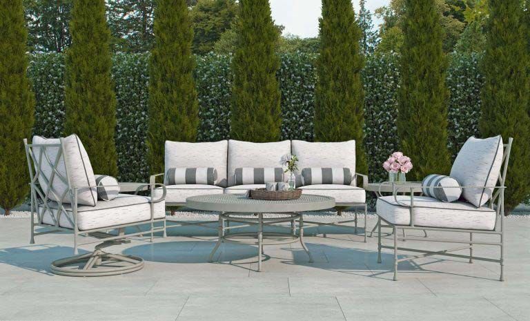 White patio seating set with sofa, chairs, and coffee table in a garden courtyard