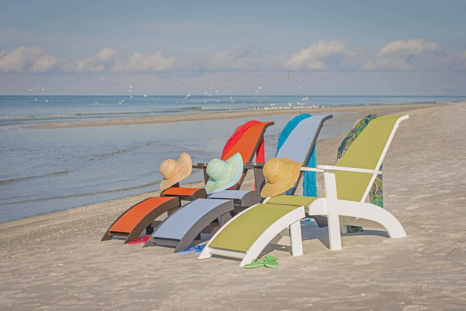 Colorful beach chairs facing the sea on a sunny sandy shoreline
