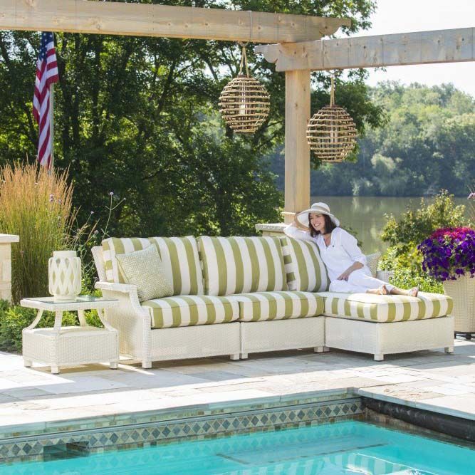 Poolside patio with striped cushions, hanging lanterns, and a woman reclining in a white sun hat