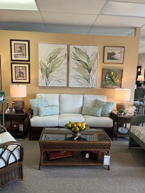 Cozy living room with beige sofa, botanical wall art, lamp-lit side tables, and glass coffee table