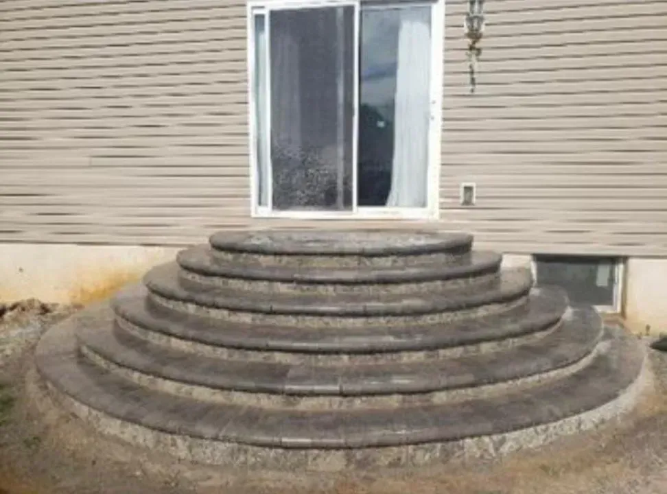Curved stone steps leading to a sliding glass door on a beige house.