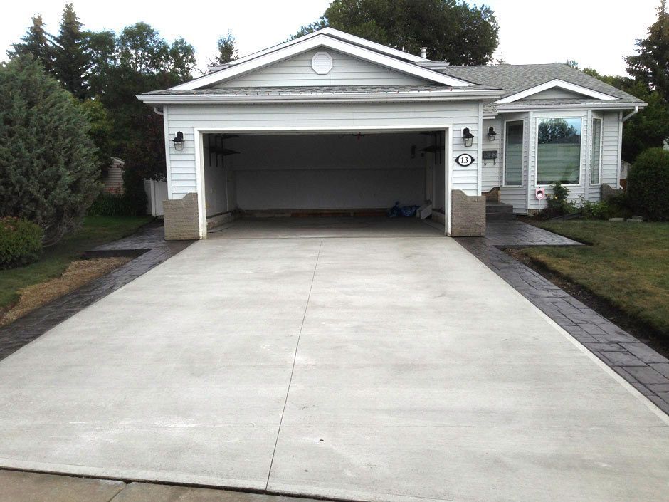 A two-car garage with an open door and a freshly paved driveway.
