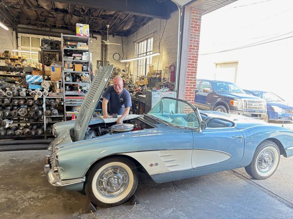 Two mechanics in gray gloves working on a car engine.
