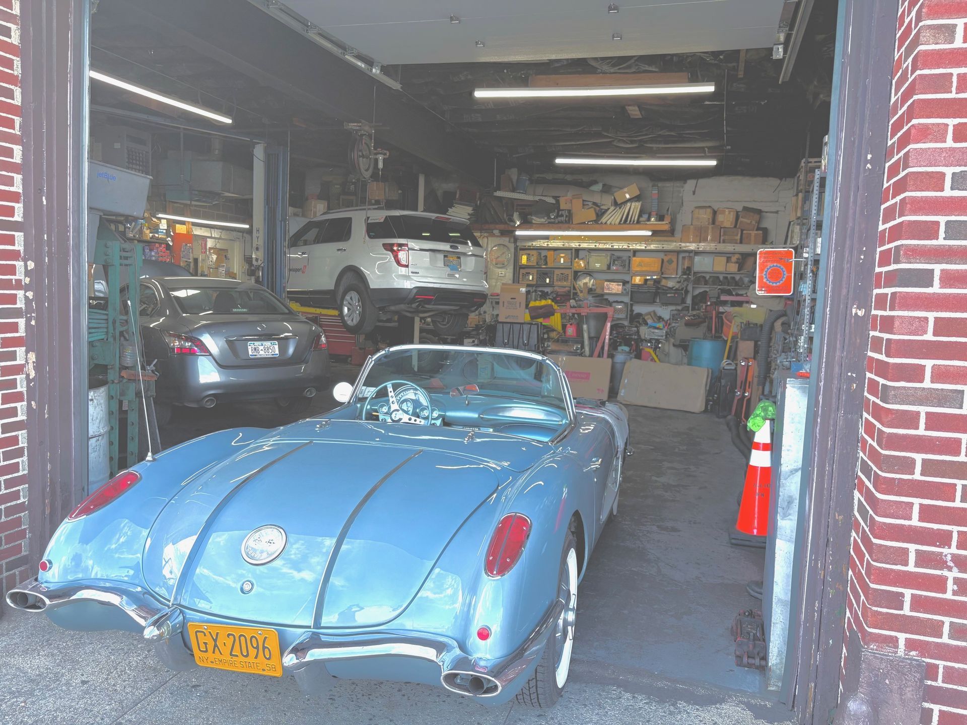 Mechanic using a wrench to work on a car engine, wearing blue work gloves.