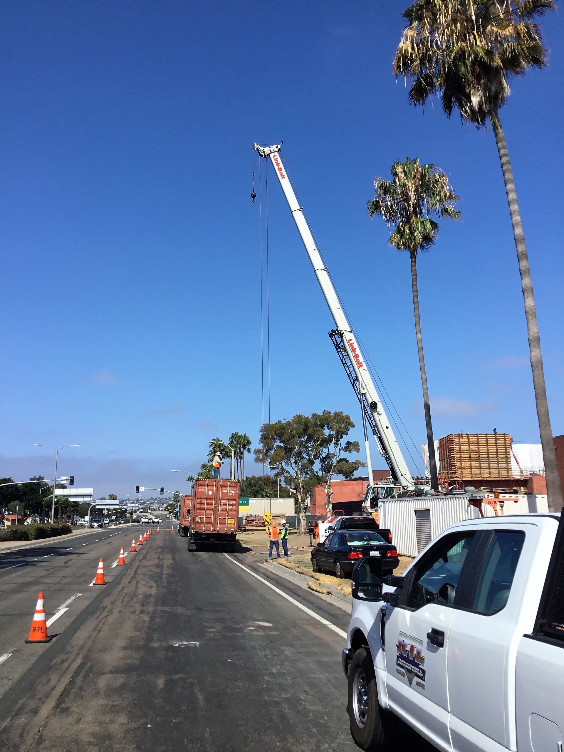 A truck is parked on the side of the road next to a crane.