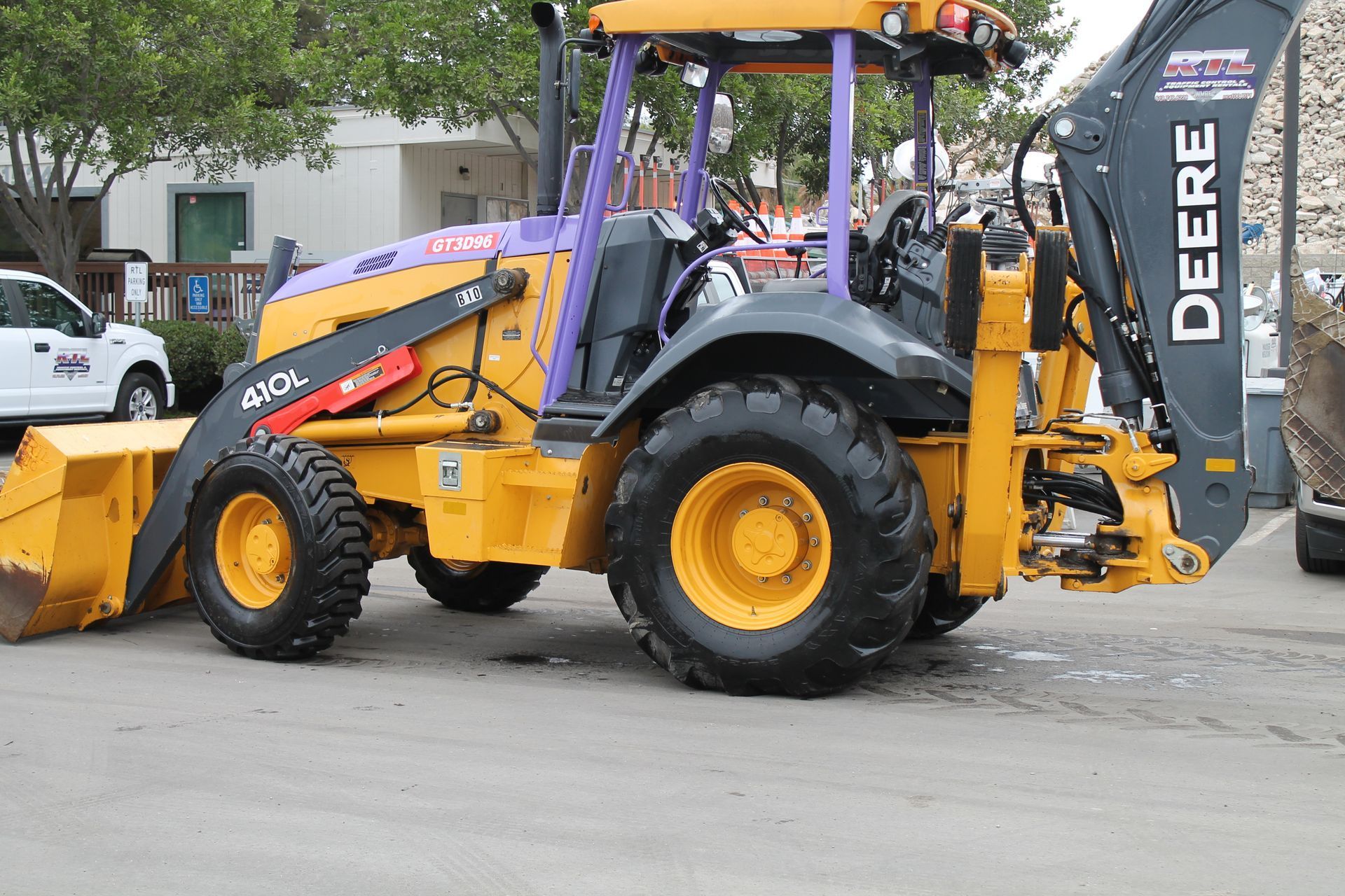 Yellow and black backhoe loader parked outdoors, showing the front bucket and rear digging arm