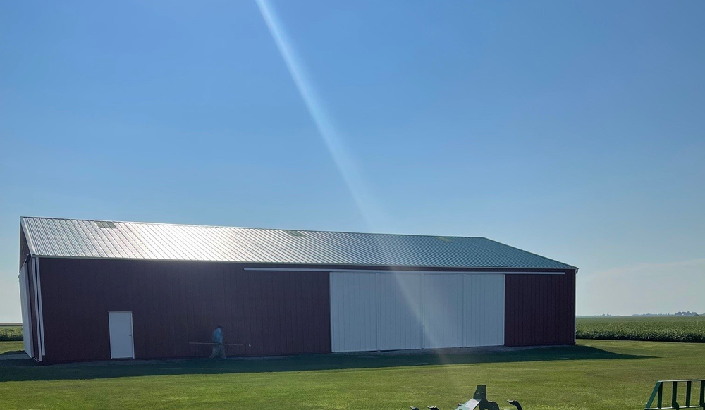 Red barn with white sliding doors on a sunny day.