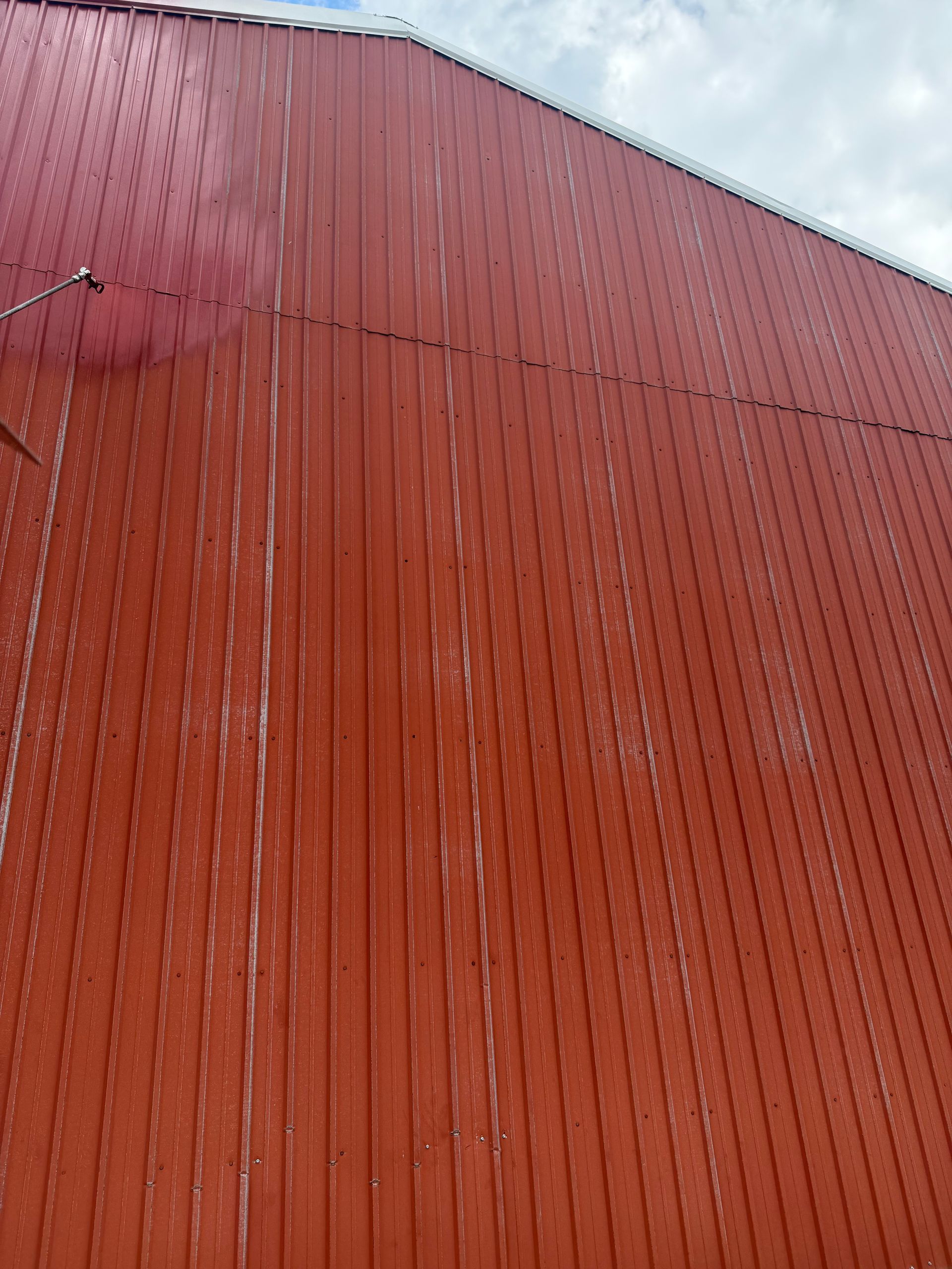 Red wooden building exterior with vertical planks, some paint flaked.