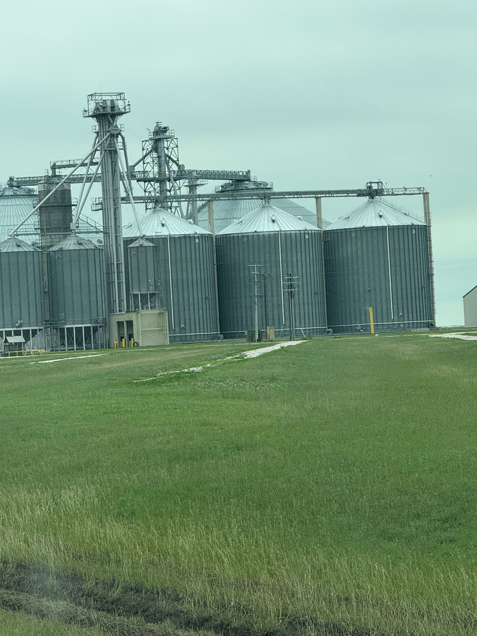 Grain silos in a field under a cloudy sky.