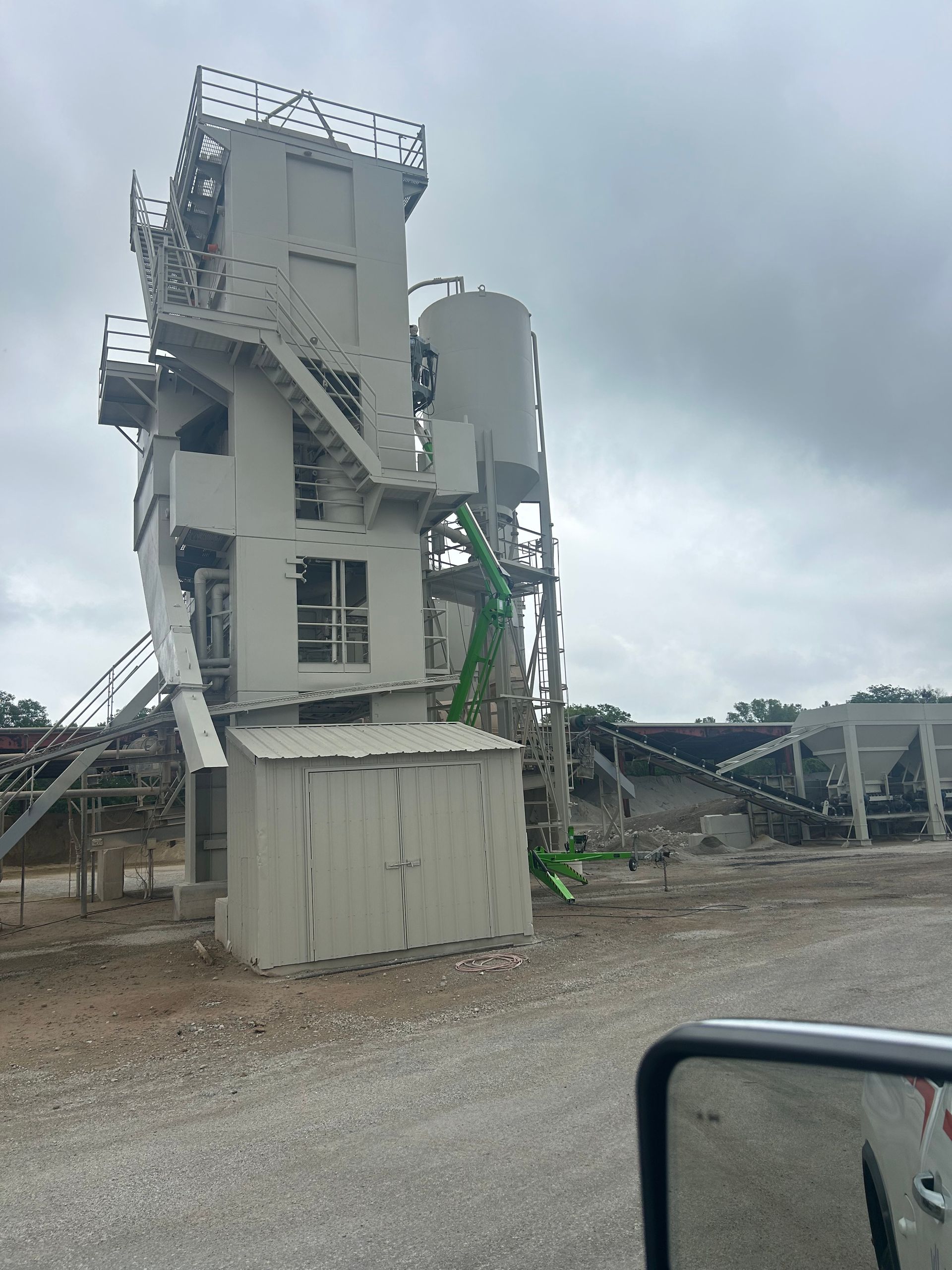 A large, industrial stone crushing and processing plant tower under a cloudy sky.