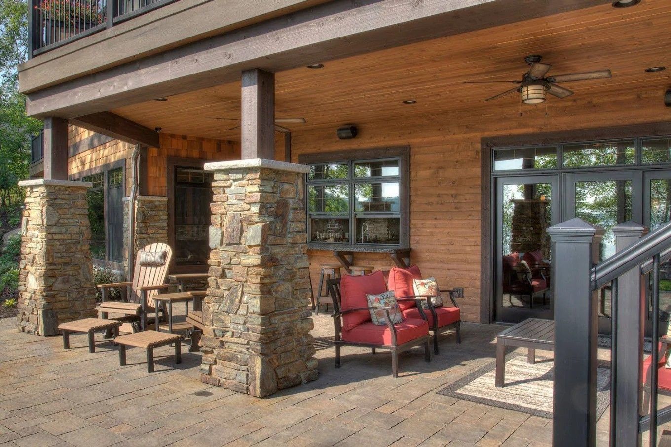 Covered patio with stone pillars, wicker chairs, red cushioned seat, and sliding glass doors