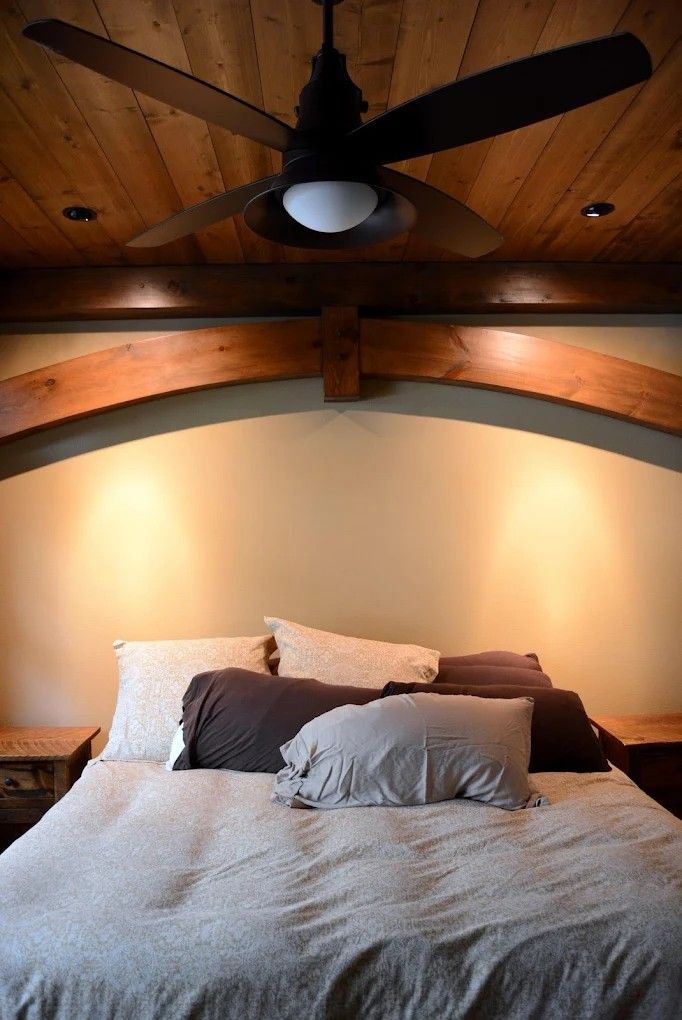 Cozy bedroom with a large bed, arched wood ceiling, and ceiling fan