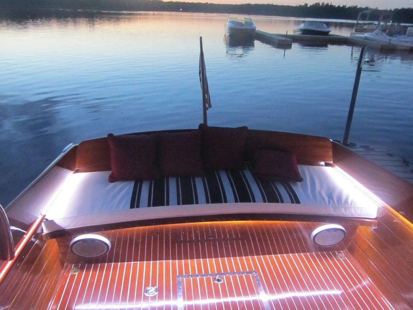 View from a wooden boat at dusk, with calm water and other boats docked ahead.
