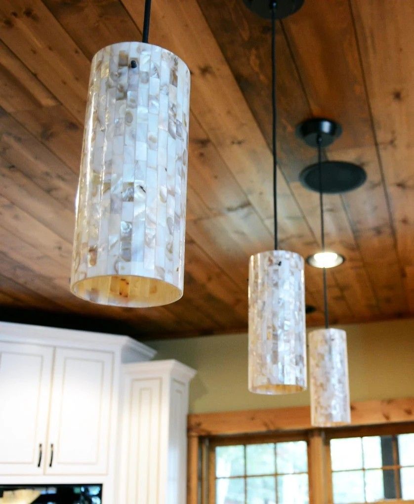 Three hanging mosaic pendant lights under a wood-paneled ceiling in a kitchen