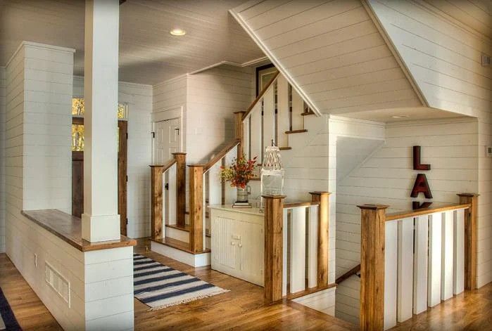 Bright hallway with wooden stairs, white walls, and a decorative wall sign in a modern home