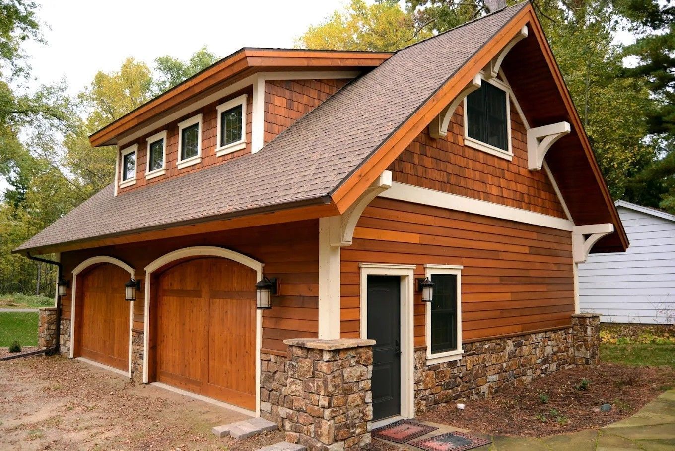 Two-story brick and wood house with a double garage and stone accents