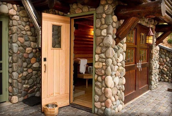 Rustic stone cabin entrance with open peach door and wooden door beside it