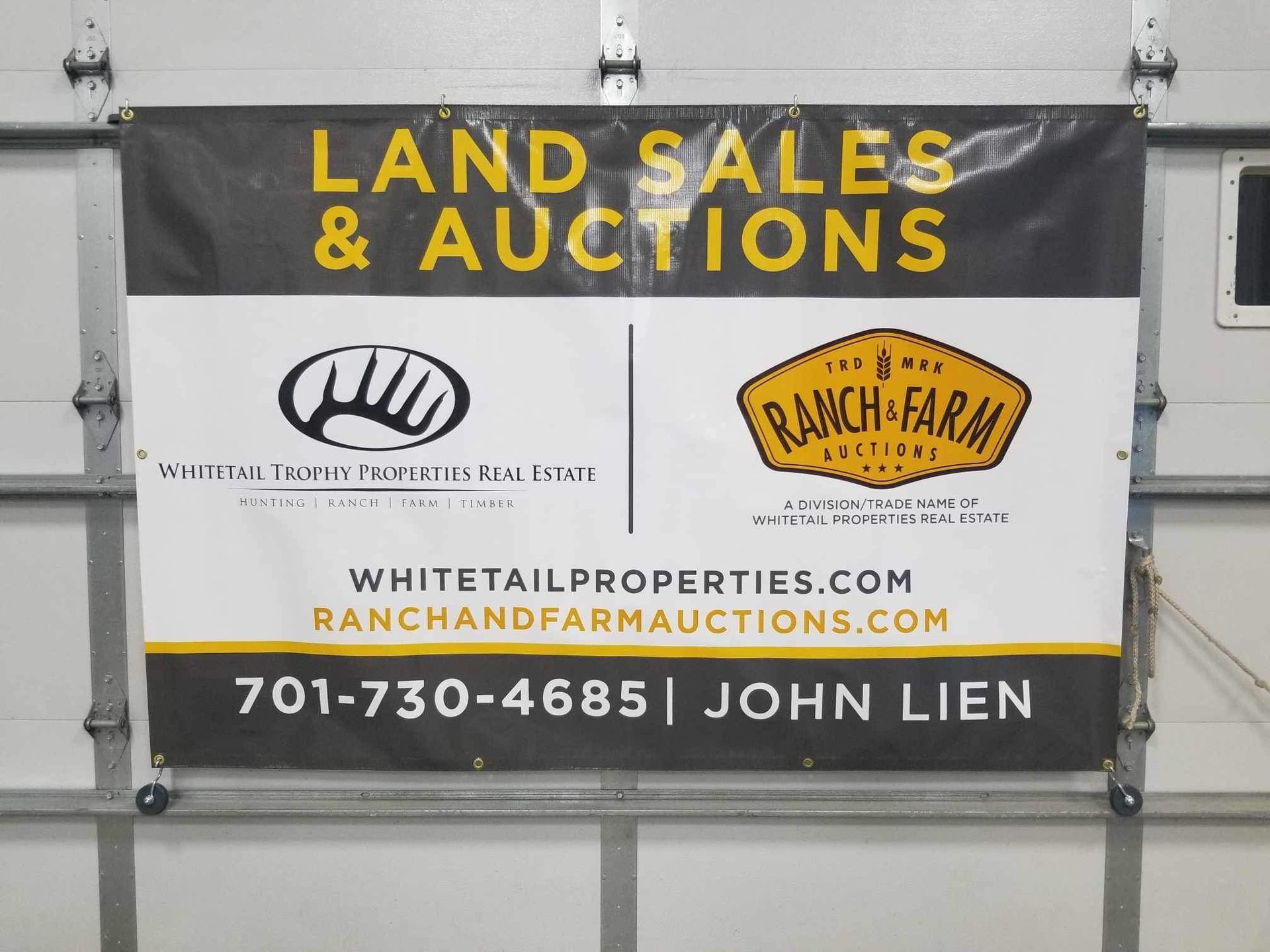 A banner for land sales and auctions hangs on a garage door