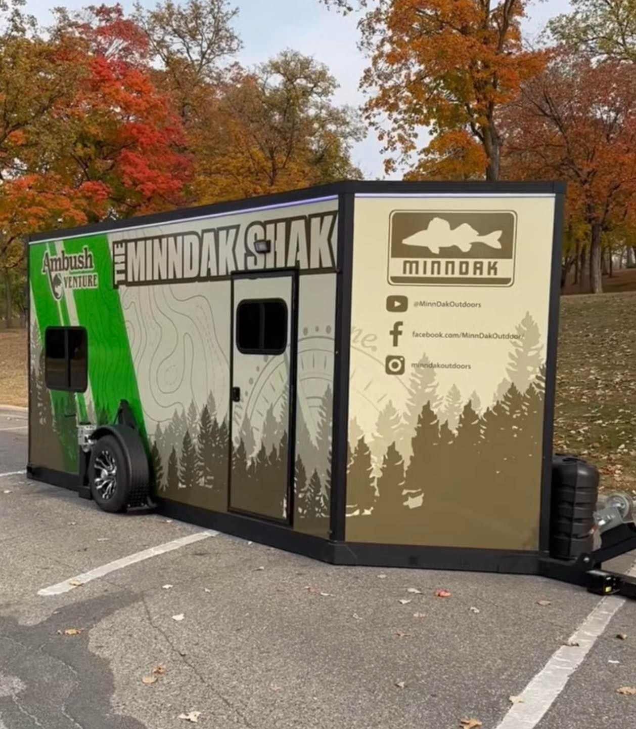 A green and white trailer with minnesota on the side is parked in a parking lot