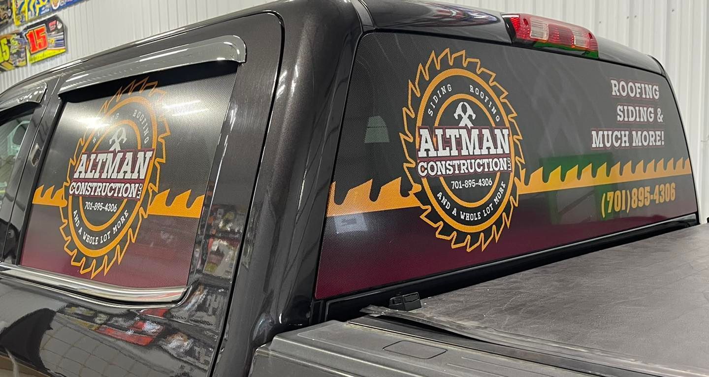 A black truck with a sticker on the back window that says altman construction.