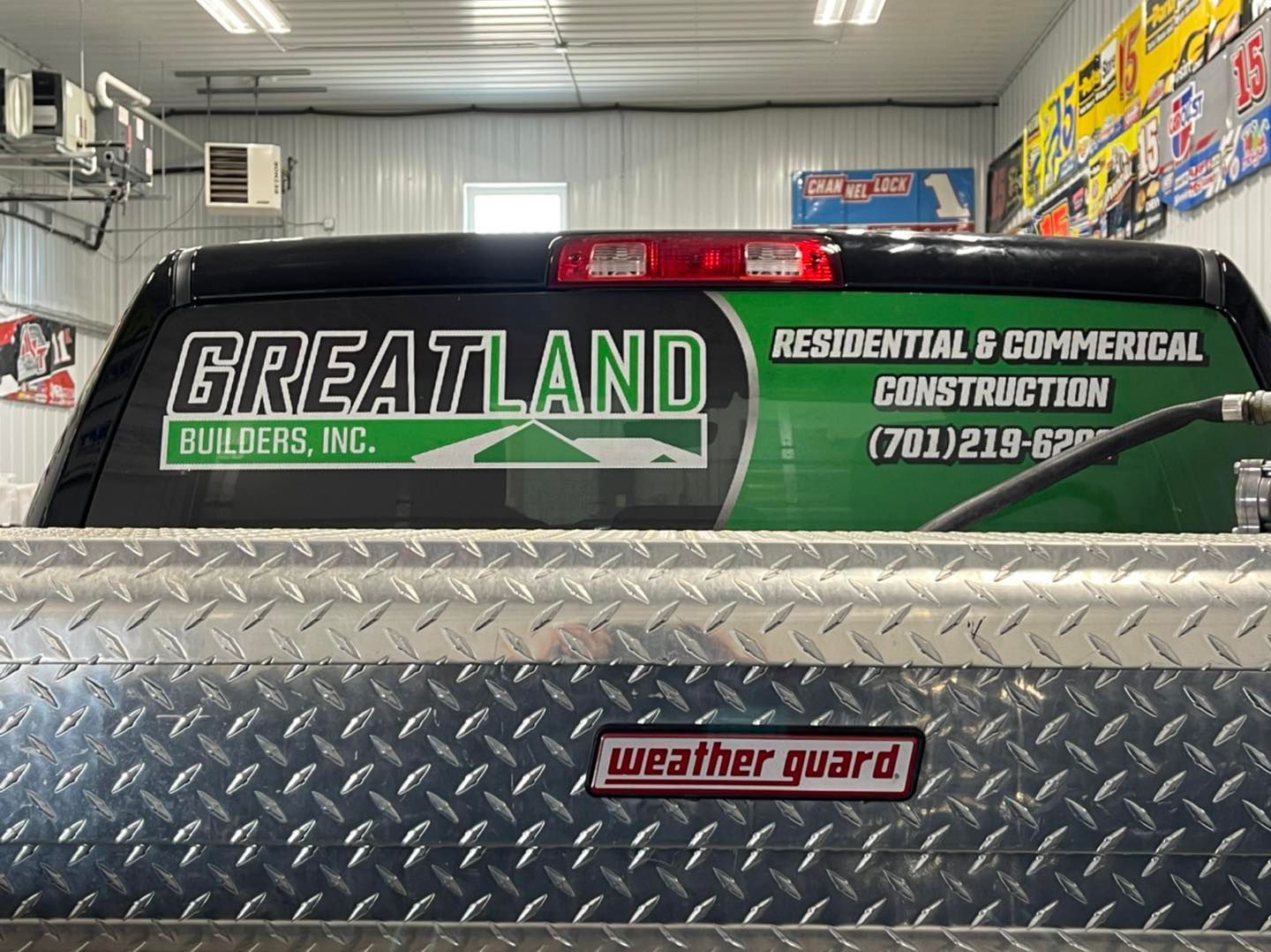 A truck with a sticker on the back window that says `` greatland residential & commercial construction ''.
