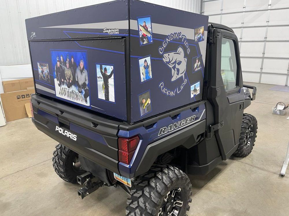 A polaris utility vehicle with a box on top of it is parked in a garage.