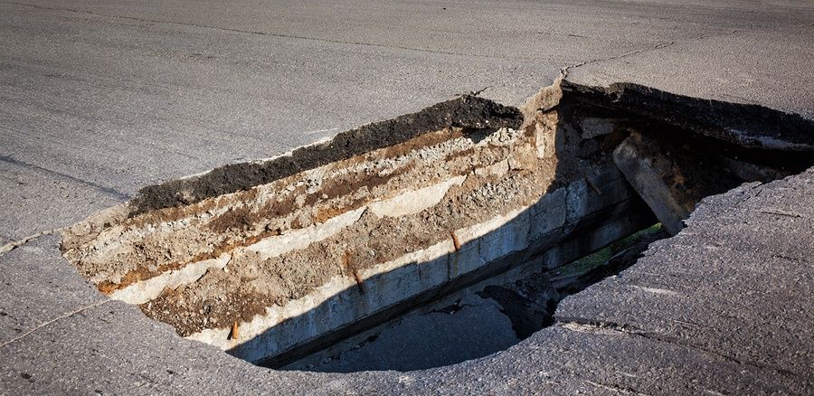 A large hole in the ground on the side of a road.
