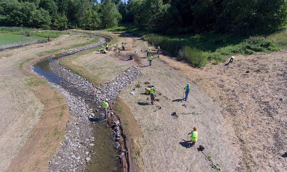 An aerial view of a group of people working on a river bank.
