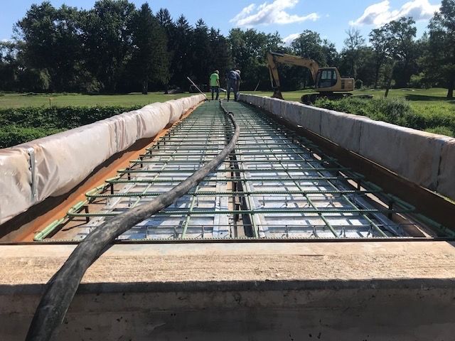 A hose is being used to pour concrete on a bridge under construction