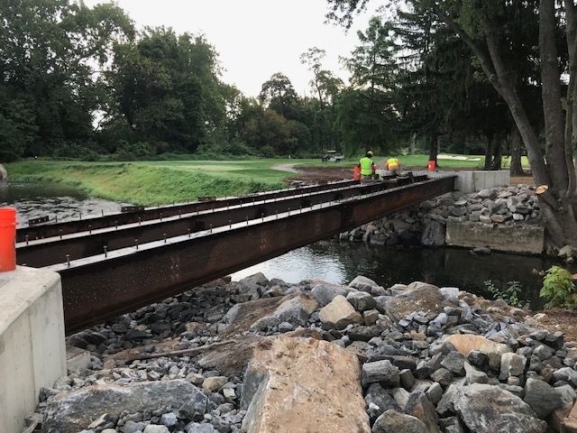 A bridge over a river with a golf course in the background