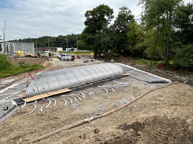 A large metal structure is sitting on top of a dirt field.