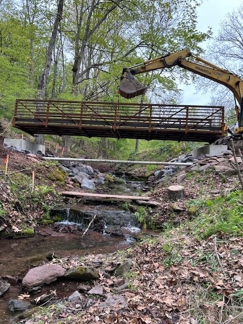 A bridge is being built over a stream in the woods.