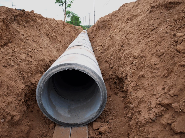 A concrete pipe is being installed in a trench.