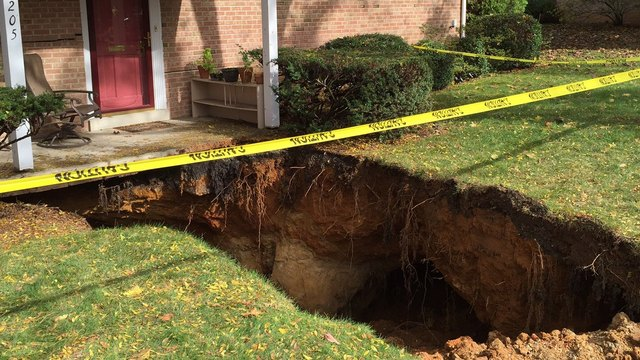 A large hole in the ground in front of a house.
