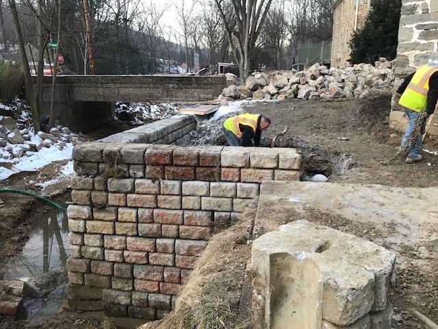 Two construction workers are working on a brick wall.