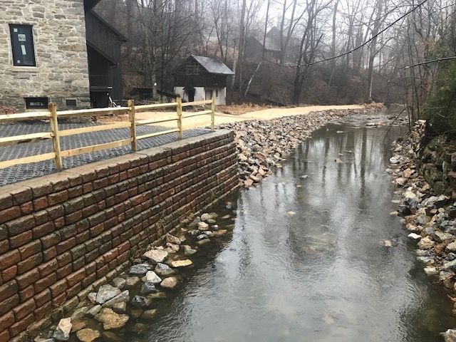 A river with a brick wall and a wooden fence surrounding it