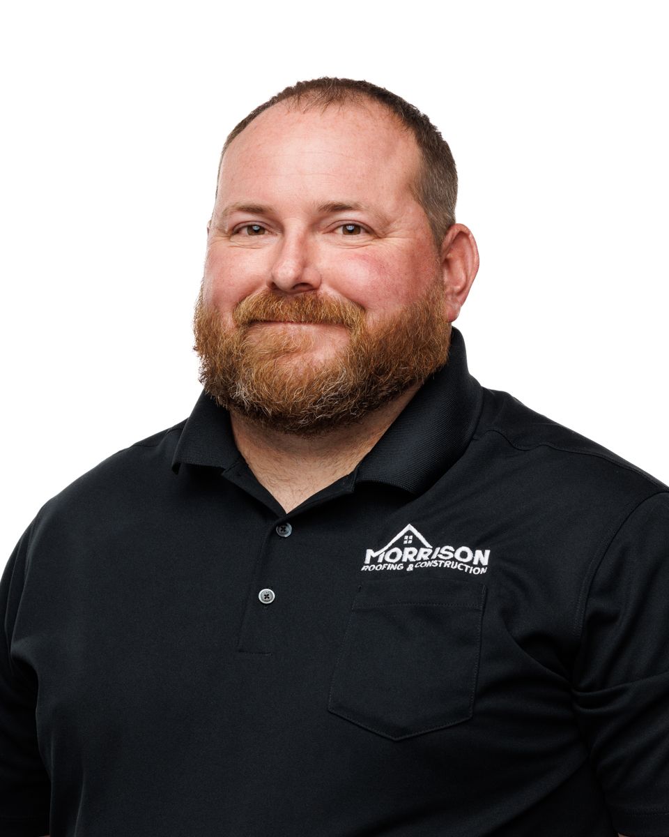 A man with a beard is wearing a black shirt and smiling.