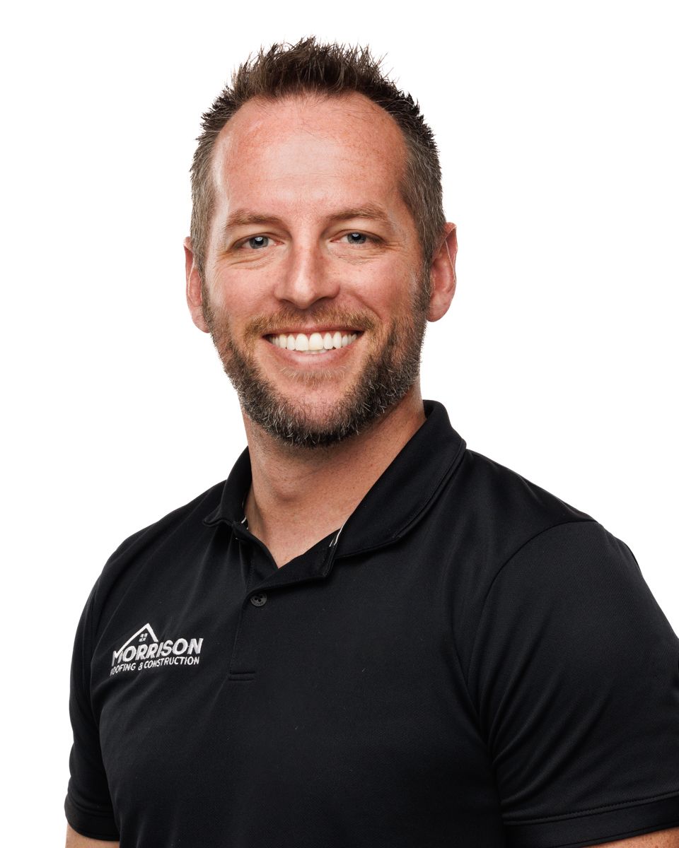 A man with a beard is wearing a black polo shirt and smiling.