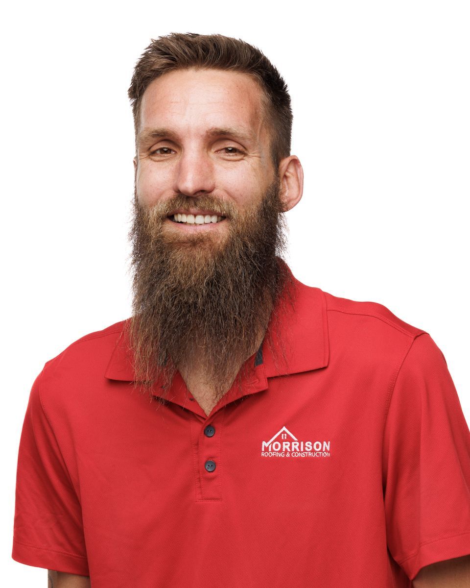 A man with a beard is wearing a red shirt and smiling.