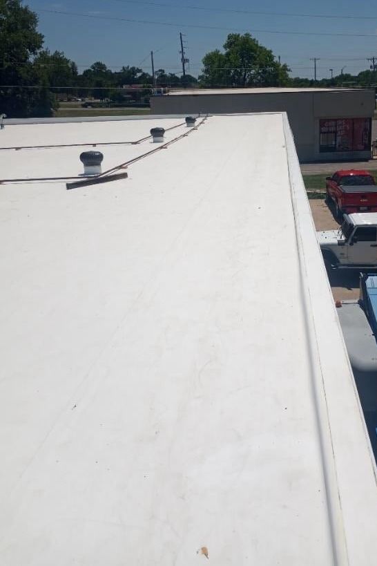 A white roof with a red truck parked on the side of it.