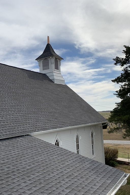 A white church with a gray roof and a bell tower.